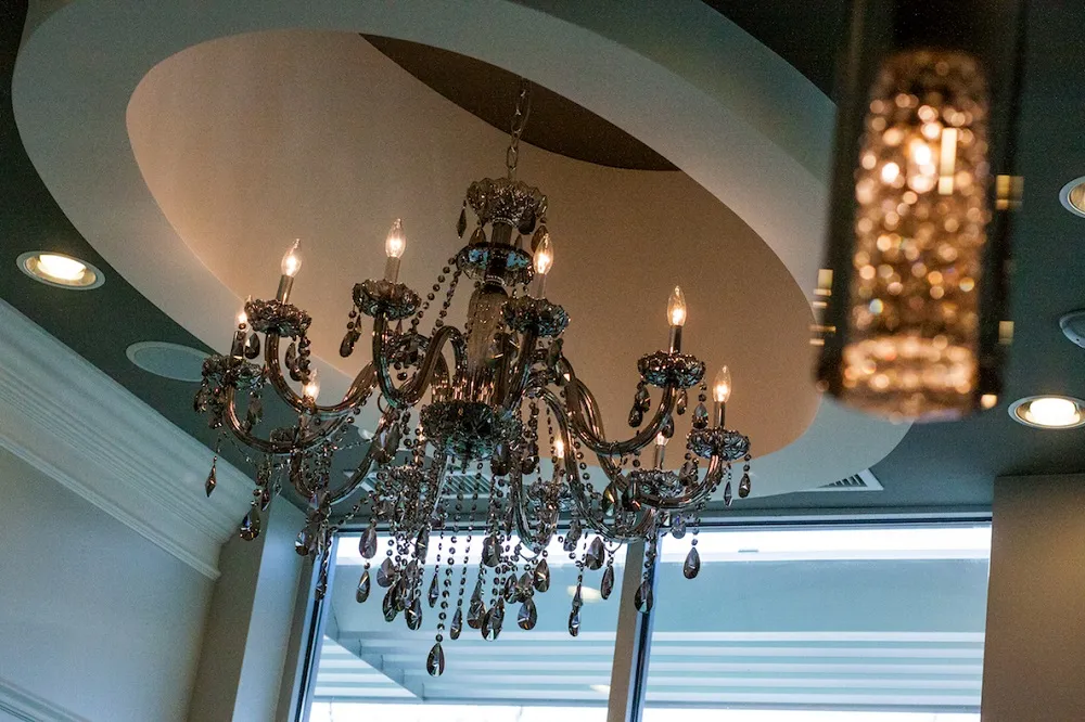 A low-angle shot looking up at an elegant, multi-tiered crystal chandelier hanging from a recessed circular ceiling