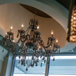 A low-angle shot looking up at an elegant, multi-tiered crystal chandelier hanging from a recessed circular ceiling