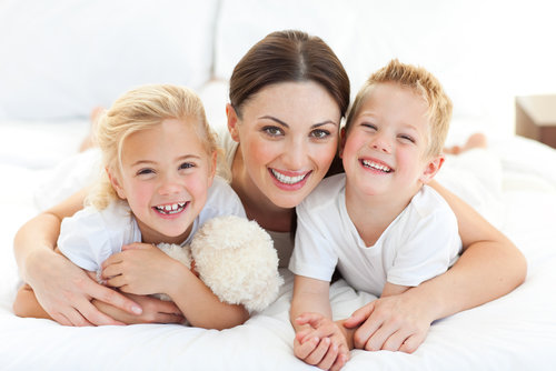 Mother with two daughters on bed
